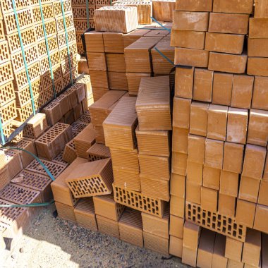 Side view of two piles of stacked orange bricks with rectangular holes tied with cyan plastic tape clipart