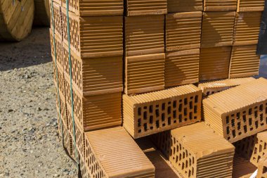 Koyu renkli plastik bantla tutturulmuş dikdörtgen delikli turuncu tuğlaların yan görüntüsü