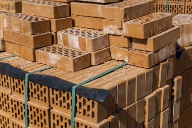 Koyu renkli plastik bantla tutturulmuş dikdörtgen delikli turuncu tuğlaların yan görüntüsü