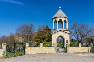 Abrameti köyündeki kilisenin çan kulesi. Asma desenli, taş çitli dövülmüş kapılar. Sonbahar renkleri, mavi gökyüzü