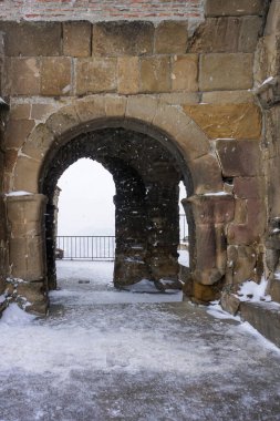 Karlı bulutlu havada Jvari Manastırı 'nın detayları. Düşen kar ve karla kaplı tarlalar görünür