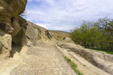 The road between the cliff and the precipice in the ancient city. Uplistsikhe is an ancient rock-hewn town. clipart