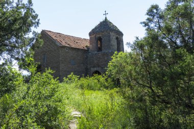 Tepedeki küçük kilise Shio-Mgvime manastırının bir parçasıdır. Arkadaki parlak mavi gökyüzü.