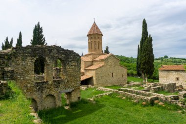 Ikalto Akademisi 'nin ana kilisesi ve kemerli camları olan taş bir bina. Clay, Qvevri 'yi taş bir duvarın altına hapsetti. Güzel selvi ağaçları