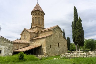 Ikalto Akademisi 'nin ana kilisesi. Kemerli giriş, çan kulesi, kiremitli çatı. Güzel selvi ağaçları