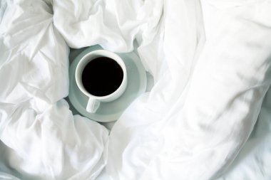 Beyaz fincan kahve yatakta