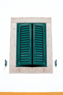The scene captures Mediterranean or tropical wooden shutters on windows charm , with warm sunlight. Ideal for travel, architecture, and lifestyle themes.