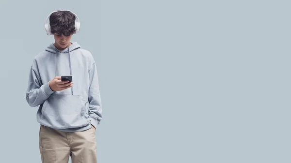 Cool Tiener Het Dragen Van Koptelefoon Verbinding Met Zijn Smartphone — Stockfoto