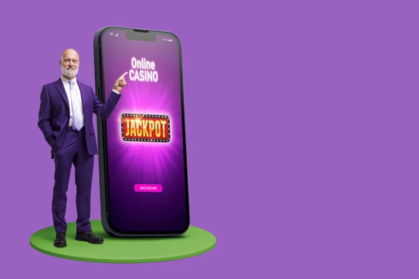 男人指着一个装有在线赌场游戏界面 赌博和赌博概念的大型智能手机屏幕 — 图库照片
