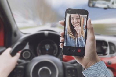Arabayı kullanırken dikkati dağılmış bir sürücü akıllı telefon kullanıyor.