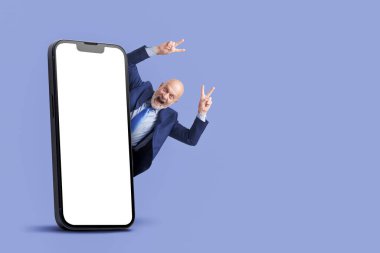 Başarılı iş adamı kollarını kaldırarak kutlama yapıyor ve büyük akıllı telefonu boş ekran, pazarlama ve iş konseptiyle birlikte kullanıyor.