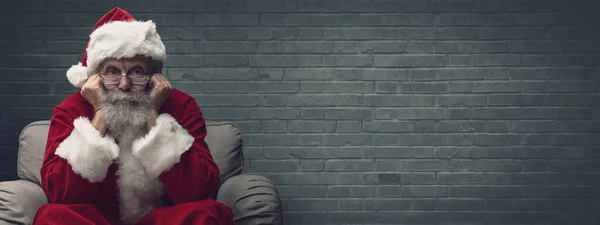 サンタクロースがアームチェアに座ってクリスマスを待っていると 彼は手に頭を休めている — ストック写真