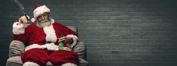 坏圣诞老人独自在家庆祝圣诞节 他抽雪茄和喝啤酒 — 图库照片