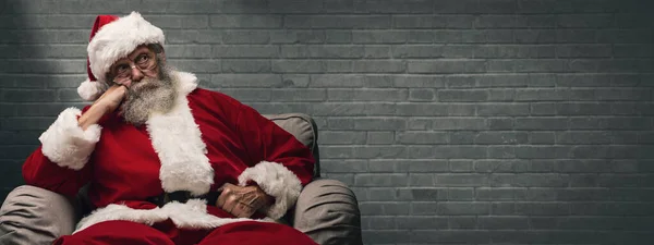 懒惰的疲倦的圣诞老人等待圣诞节 他坐在扶手椅在家和休息的头在手 — 图库照片