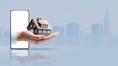 Real estate agent hand showing a model house in a smartphone screen, real estate app concept, copy space