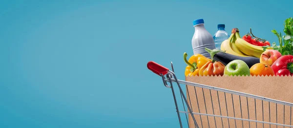 Supermarket shopping cart full of groceries, sale and retail concept, copy space