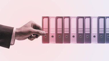 Corporate businessman taking a ring binder from the office archive, data storage and catalog concept, vintage style design