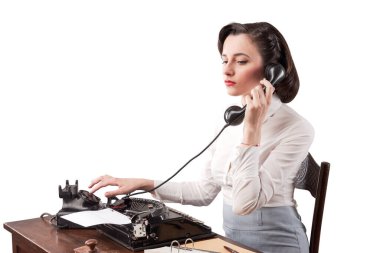 Güzel, verimli bir sekreter ofiste masa başında oturuyor ve çalışıyor. Klasik tarzda bir telefon görüşmesi yapıyor.