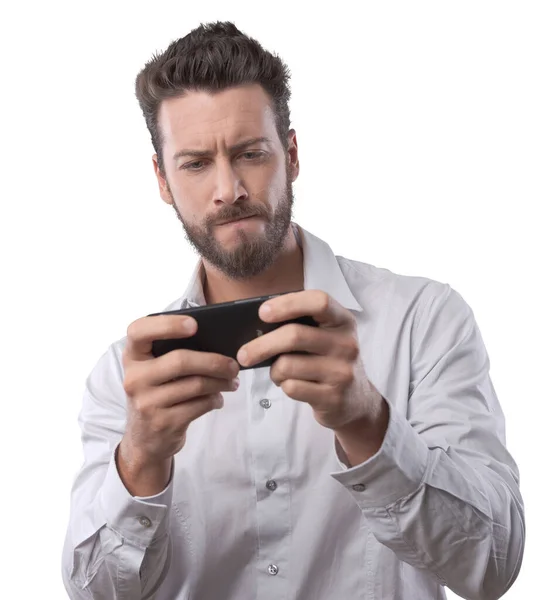 一个年轻英俊的男人在白色背景下玩他的智能手机 — 图库照片