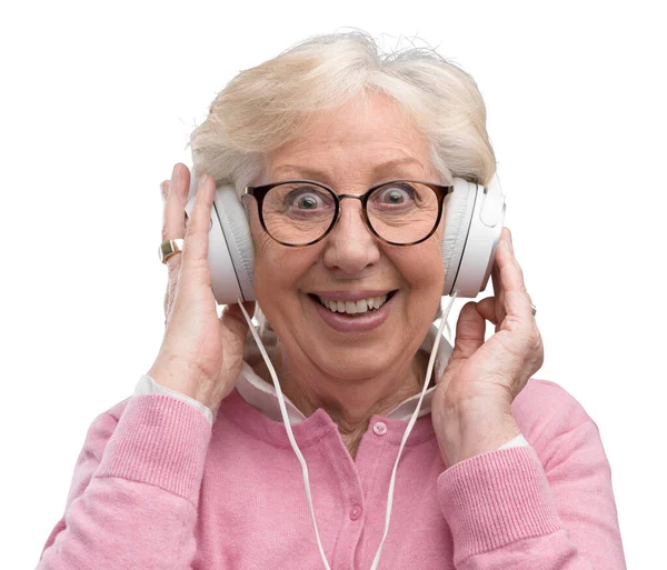 彼女は快活で楽しんで幸せな年配の女性の身に着けているヘッドフォンといくつかの良い音楽を聴いて — ストック写真