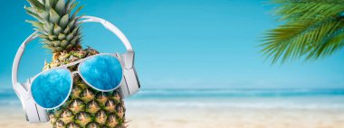 Tropik plajlarda kulaklık takan komik ananas ve güneş gözlüğü, yaz tatilleri ve parti konsepti, uzay kopyaları.