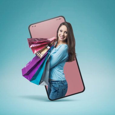 Cheerful smiling woman shopping with lots of colorful bags in a smartphone videocall and smiling, online  shopping concept