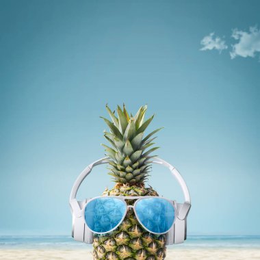 Tropik plajlarda kulaklık takan komik ananas ve güneş gözlüğü, yaz tatilleri ve parti konsepti, uzay kopyaları.