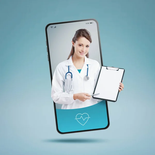 Smiling female doctor on smartphone screen giving a medical prescription: online doctor video consultation concept