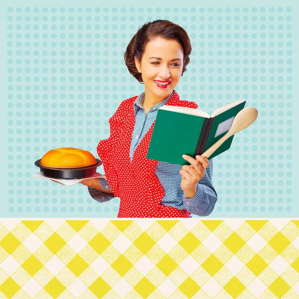 Smiling retro housewife holding a cookbook and a baking tin with a homemade cake