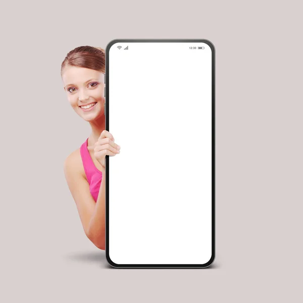 Glückliche Junge Frau Lächelt Und Blickt Hinter Ein Großes Smartphone — Stockfoto