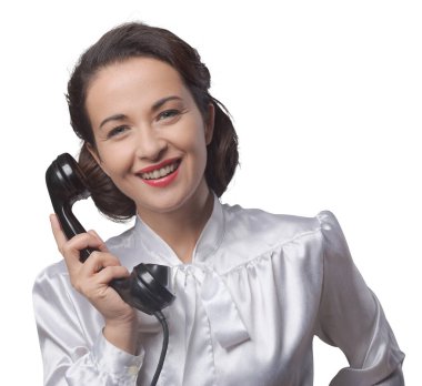 Çekici klasik sekreter telefonda kameraya gülümsüyor.