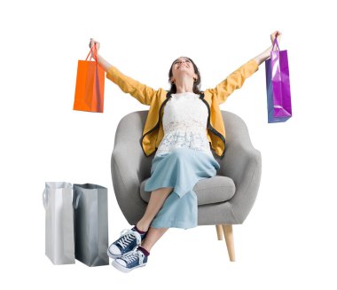 Alışveriş çantaları çok neşeli mutlu alışverişkolik kadın, o bir koltukta oturuyor ve kolları kaldırdı ile kutluyor