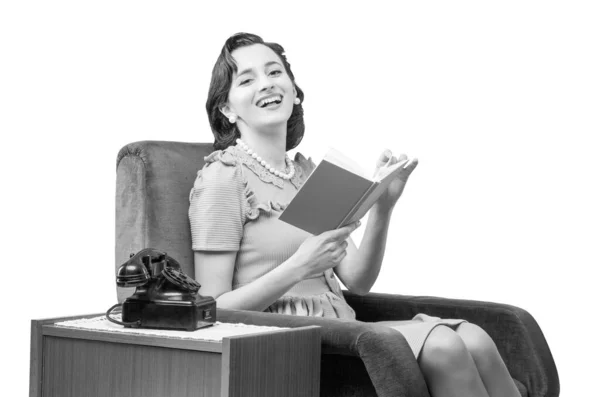 复古风格的女人坐在扶手椅上看书 她在镜头前开心地微笑着 — 图库照片