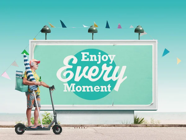 快乐的老年人骑着电动车去海滩 背景上挂着激励人的海报 享受每一个时刻 — 图库照片