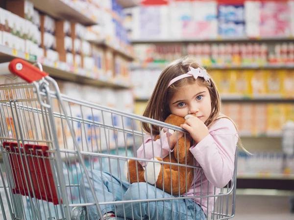 Portret Uroczej Dziewczynki Supermarkecie Siedzi Wózku Sklepowym Przytula Swojego Misia — Zdjęcie stockowe