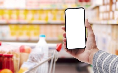 Arka planda boş ekran ve süpermarket içi olan akıllı telefonu olan bir kadın, çevrimiçi market alışverişi kavramı