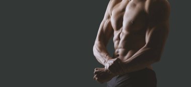 Kendine güvenen atletik gömleksiz adam mükemmel kaslı vücudunu gösteriyor; egzersiz ve fitness konsepti