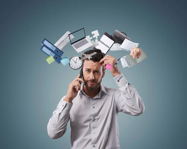 電話を持っている混乱したビジネスマン 彼はビジネスアイテムやオフィス用品に囲まれています 効率性 ストレス管理の概念 — ストック写真