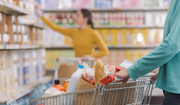 食料品店の女性 彼女はショッピングカートを押し 製品を購入しています — ストック写真