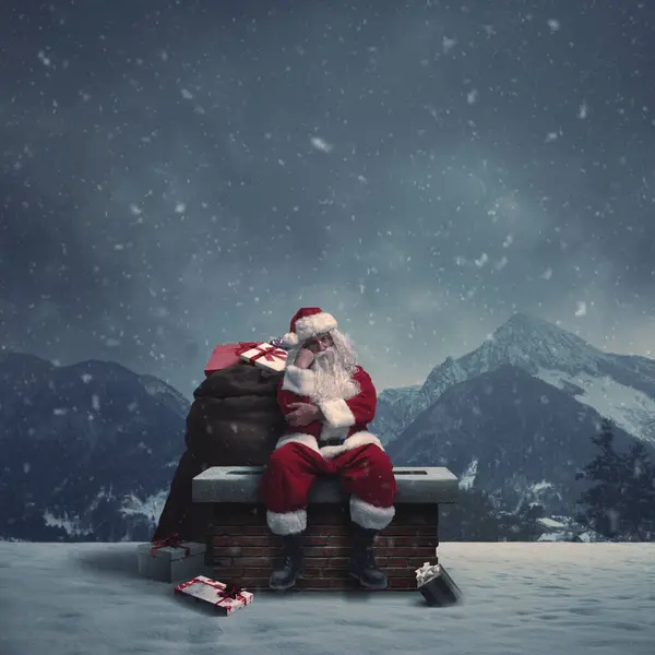 厌倦了的圣诞老人送来圣诞礼物 他坐在雪堆下的烟囱上 — 图库照片
