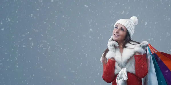 雪の下でクリスマスショッピングをしている幸せな女性 彼女は笑顔で多くのバッグを保持しています — ストック写真