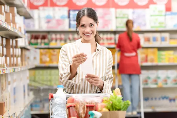Šťastná Mladá Žena Nákupním Vozíkem Plným Potravin Drží Účtenku Obchodu — Stock fotografie
