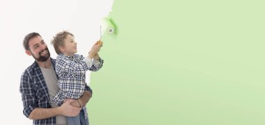 Genç baba ve tatlı çocuk birlikte poz veriyorlar ve gülümsüyorlar, yeni evlerini boyuyorlar.