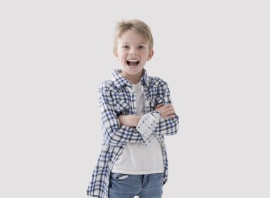 Kollarını kavuşturup gülümseyen, beyaz arka planda poz veren sevimli, mutlu sarışın çocuk.