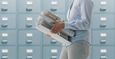 Female office worker carrying folders and files in the archive, administration and business concept clipart
