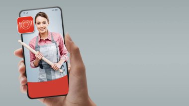 Akıllı telefonunda merdane tutan kadın aşçı: çevrimiçi profesyonelleri işe al