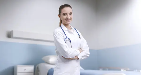 Junge Lächelnde Ärztin Posiert Mit Verschränkten Armen Krankenhauszimmer Medizinische Betreuung — Stockfoto