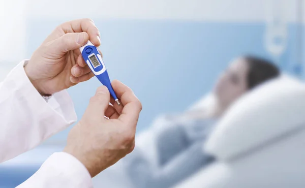 Professional doctor holding a thermometer, he is taking a patient\'s temperature at the hospital