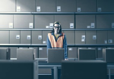 Young female worker checking packages and orders in the warehouse clipart