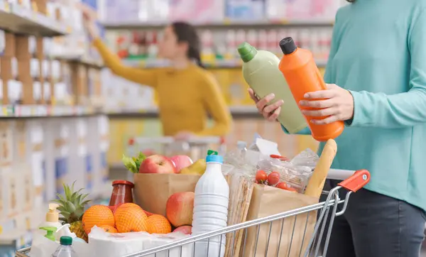 Mujer Comprando Productos Tienda Comestibles Está Comparando Dos Botellas Detergentes Imagen De Stock